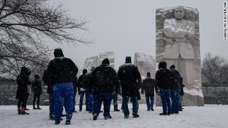 Visitors look to the Martin Luther King, Jr. Memorial as snow falls in Washington, DC, Sunday.