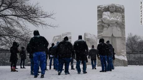 Visitors look to the Martin Luther King, Jr. Memorial as snow falls in Washington, Sunday, Jan. 16, 2022. Ceremonies scheduled for the site on Monday, to mark the Martin Luther King, Jr. national holiday, have been canceled because of the weather. (AP Photo/Carolyn Kaster)