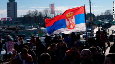 Torcedores agitam a bandeira sérvia enquanto o tenista sérvio Novak Djokovic chega ao aeroporto Nikola Tesla em Belgrado, Sérvia, na segunda-feira, 17 de janeiro. 