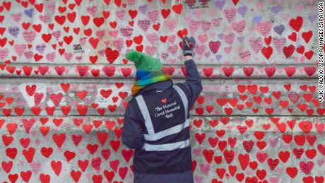 Волонтер рисует сердечки на Национальной мемориальной стене Великобритании, посвященной коронавирусу.
