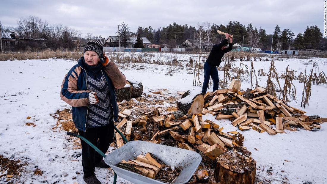 A farmer in Muratove, Ukraine, chops wood while family members collect it to sell to a nearby Ukrainian army base.