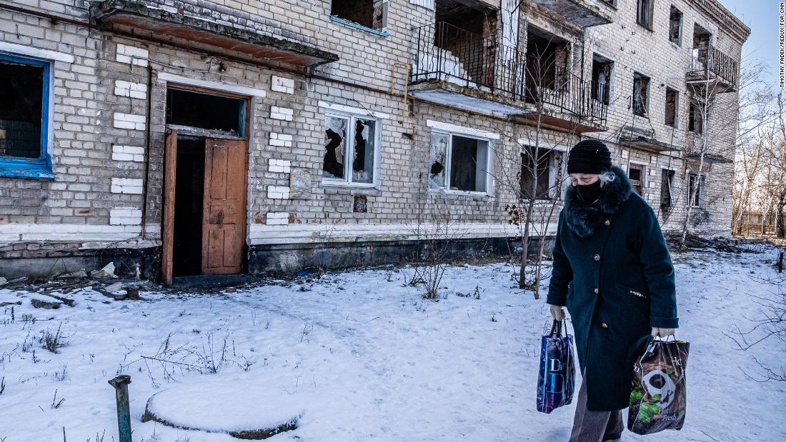 A woman walks past a damaged apartment building in Marinka. &quot;The mood was somber, depressed and resigned,&quot; Fadek said. &quot;People are going through the motions of their daily lives.&quot;