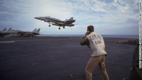 Crew watching a fighter jet landing on USS Kitty Hawk during a US-led allied air strike on Iraq, reinforcing UN post-Gulf War resolutions on January 19, 1993.