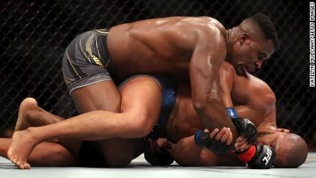 Ngannou grapples on the ground with Gane. 