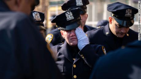 Tears are shed for slain NYPD Officer Jason Rivera as his remains are brought by procession to a funeral home Sunday in New York City.