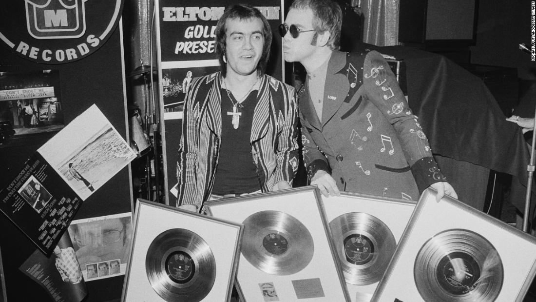 John and his songwriting collaborator, Bernie Taupin, hold gold records in 1973. Taupin has written the lyrics for many of John&#39;s songs over his career, and the two have worked together for decades.