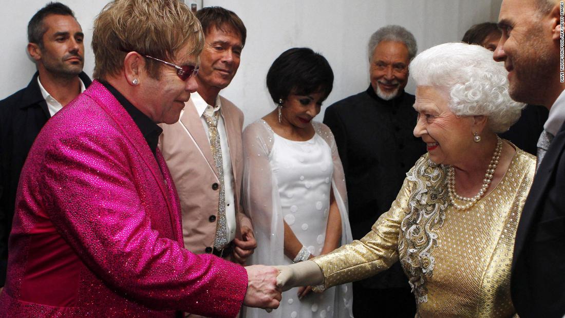 Britain&#39;s Queen Elizabeth II shakes hands with John at her Diamond Jubilee Concert in 2012. In 1998, the Queen knighted John for his music and charity work.