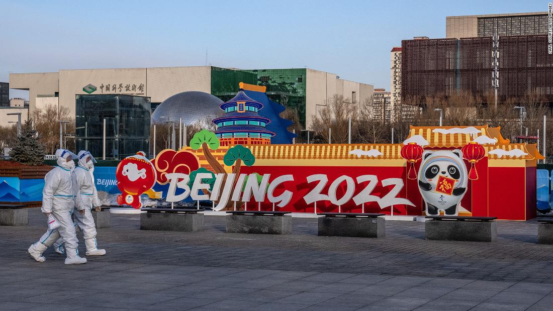 周三，身穿个人防护服的人们走过北京的冬奥会展厅。