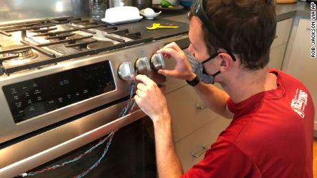 Researcher Eric Lebel attaches sensors to a stove to measure how often it is used. 