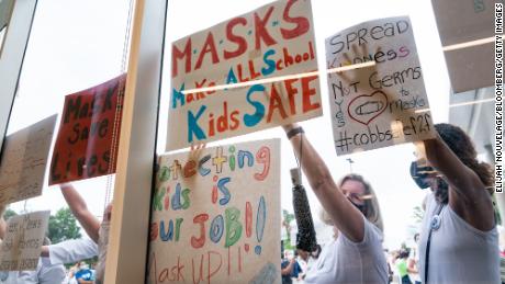 Pro-mask demonstrators hold signs during a rally over the Cobb County School District&#39;s optional mask policy on August 19, 2021, in Marietta, Georgia.