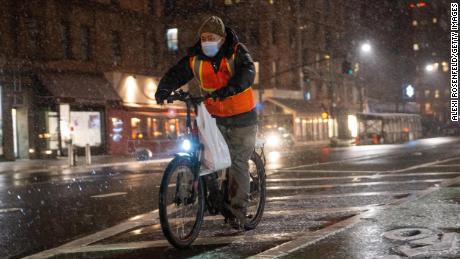  A food delivery driver on a bicycle rides in the snow on January 28, 2022, in New York City.