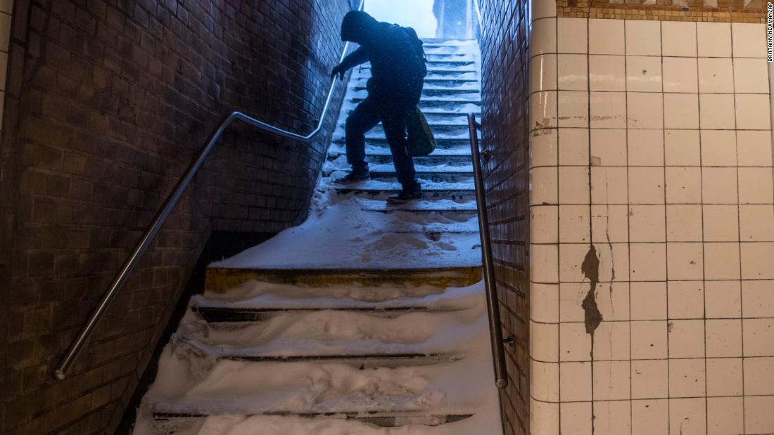 A man carefully walks down snow-covered subway stairs in Brooklyn, New York, on Saturday.