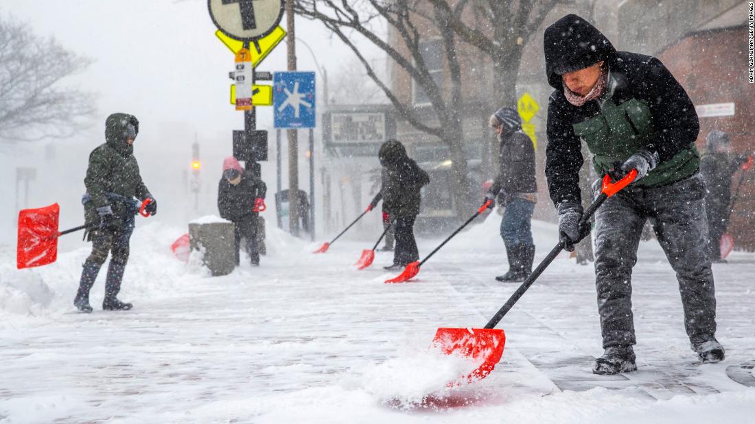 People shovel outside of the Davis Square MBTA station in Somerville, Massachusetts.