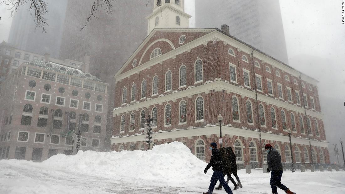 People walk in the snow outside Faneuil Hall, Saturday, in Boston, Massachusetts.