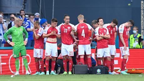 Denmark&#39;s players look dejected as teammate Christian Eriksen (hidden) receives medical treatment during the Euro 2020 match against Finland.