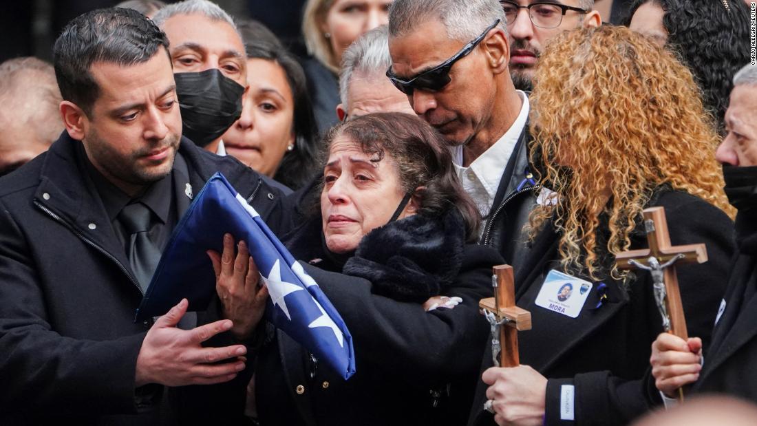 Mora&#39;s mother holds a flag from his casket.