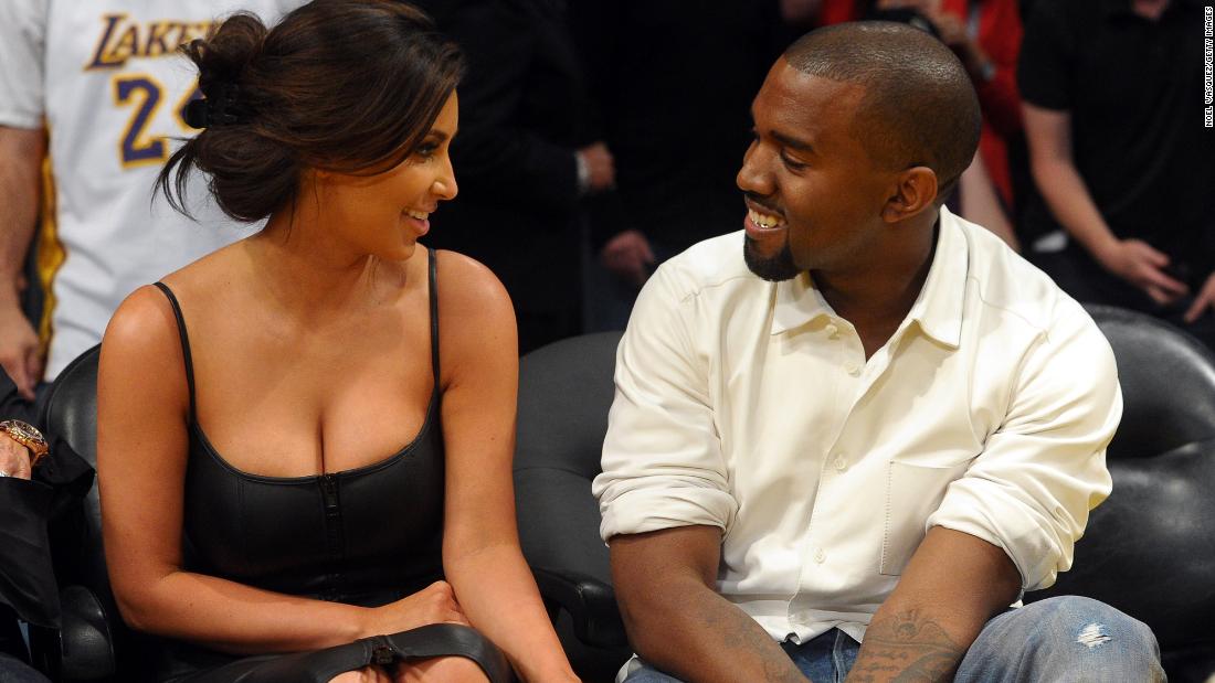 West and Kim Kardashian talk from their courtside seats at an NBA playoff game in 2012. They married in 2014.