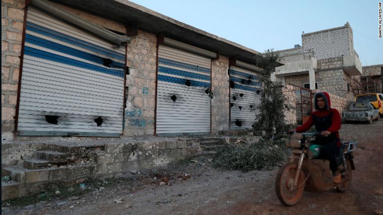 A man rides his motorcycle past damaged buildings after a US military operation in the Syrian village of Atmeh in Idlib province on February 3, 2022.