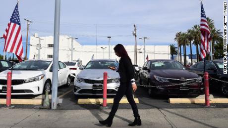 A pedestrian walks past a certified pre-owned car sales lot in Alhambra, California on January 12, 2022. 