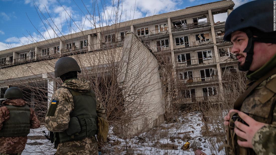Ukrainian soldiers walk past a destroyed building in Marinka.