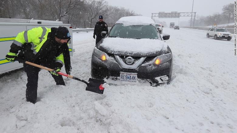 Os policiais de St. Louis, Eric Moran, à esquerda, e Scott Christian ajudam um motorista que ficou preso na neve em uma saída da rodovia na quinta-feira, 3 de fevereiro.