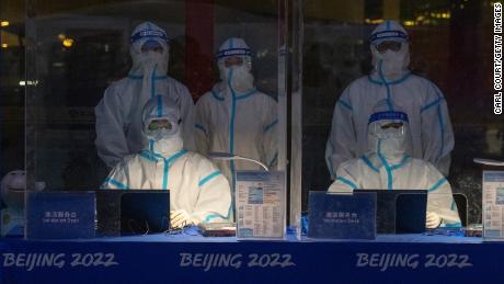 مسؤولون يرتدون معدات الحماية الشخصية ينتظرون التحقق من صحة الاعتماد الأولمبي للأشخاص الذين يصلون إلى مطار العاصمة بكين الدولي في 24 يناير.