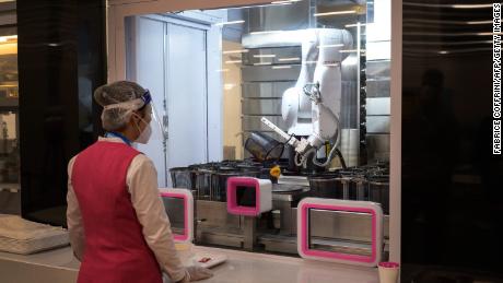 عامل ينتظر روبوتًا يعالج طلبًا في قاعة الطعام بمركز الصحافة الرئيسي لدورة الألعاب الأولمبية الشتوية لعام 2022 في بكين.