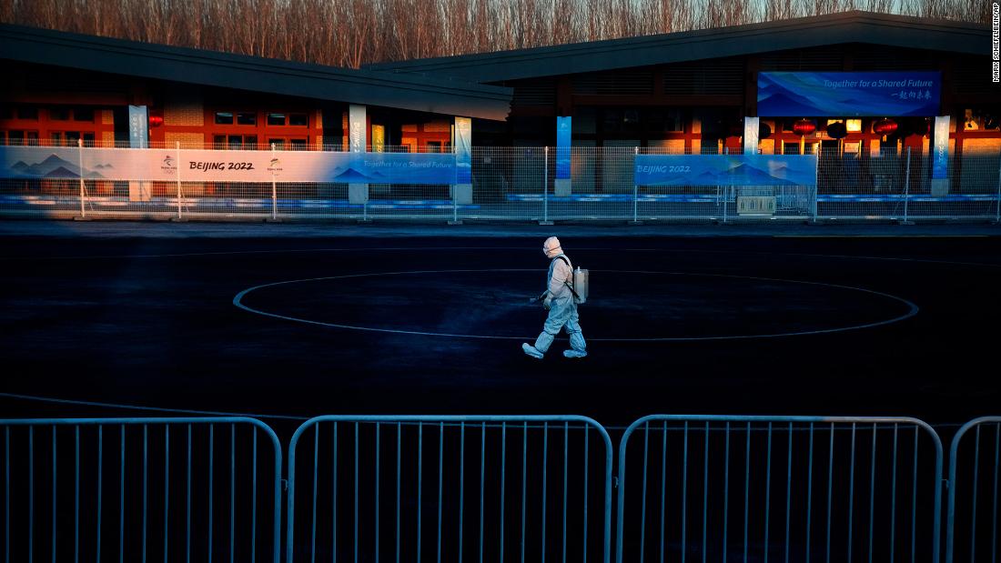 A worker wearing a protective suit sprays disinfectant at a screening checkpoint for arriving athletes on February 1.