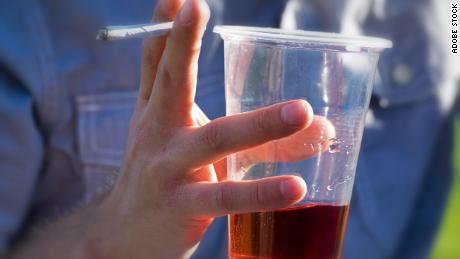 A person drinks an alcoholic beverage while smoking cannabis. Adults who reported using cannabis and alcohol also said they drove under the influence of these drugs, a new study found. 