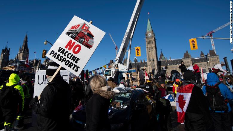 People hold signs and wave flags along Wellington Street in front of Parliament Hill on February 5 as part of the Freedom Convoy protest.