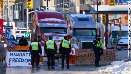 Police stand near protesters Monday after the mayor of Ottawa declared a state of emergency in the Canadian capital. A 10-day protest by truck drivers over Covid-19 restrictions has gridlocked its city center.