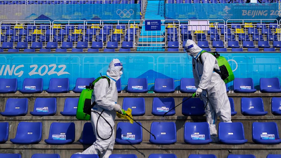 Workers in protective gear disinfect seats after the big air competition on February 9.
