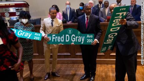 Montgomery Mayor Steven Reed, second from left, poses with Fred Gray Jr. and Stanley Gray after the city council voted unanimously to rename Jefferson Davis Avenue after Gray&#39;s father, civil rights attorney Fred Gray last year.