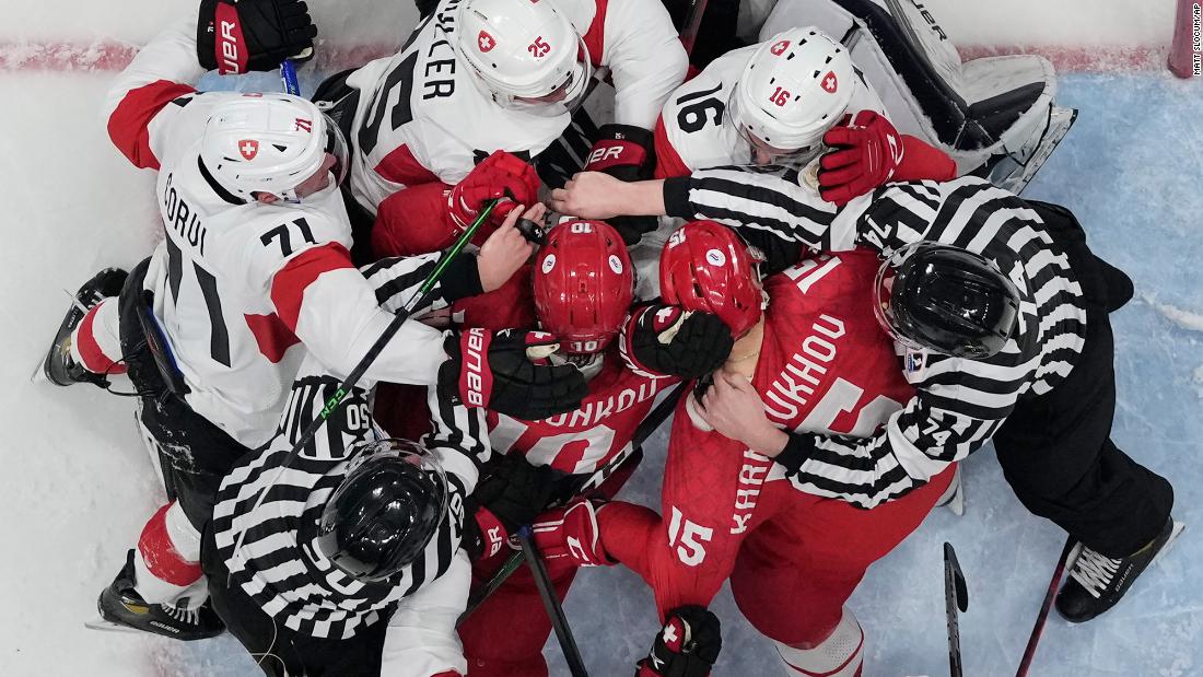 Officials try to separate hockey players from Switzerland (white helmets) and the Russian Olympic Committee during a goalmouth scrum on February 9. It was the first game of the men&#39;s hockey tournament.