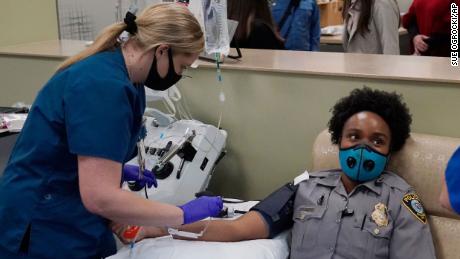 Oklahoma City police officer Erica Jackson looks away as phlebotomist Ashley Jones prepares to take her blood for a convalescent plasma donation. 