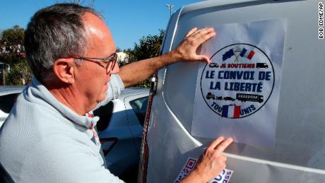 A man puts a poster reading &quot;Liberty Convoy&quot; on a van before departing for Paris, in Bayonne, southwest France, on Wednesday.