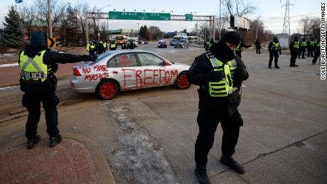 A polícia retira manifestantes e seus veículos de um bloqueio na entrada da Ambassador Bridge na manhã de sábado em Windsor, Canadá. 