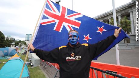A protester with a New Zealand flag stands in front of parliament buildings on the fourth day of demonstrations against Covid-19 restrictions in Wellington on February 11.