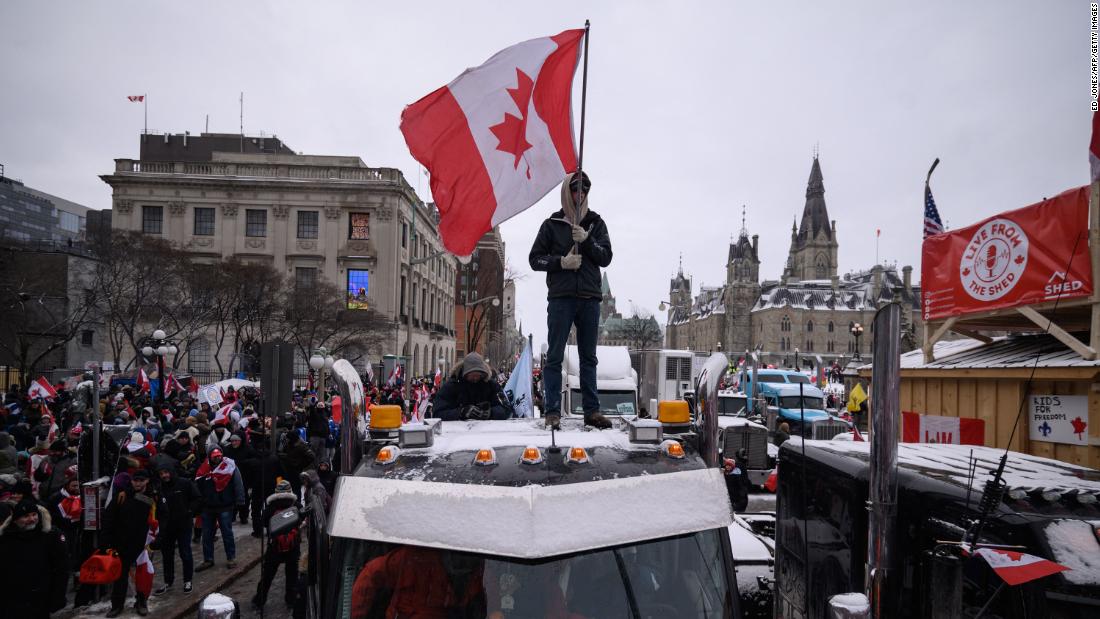 A demonstrator stands atop a truck holding a Canadian flag during a protest outside the Canadian Parliament in Ottawa on Saturday, February 12.