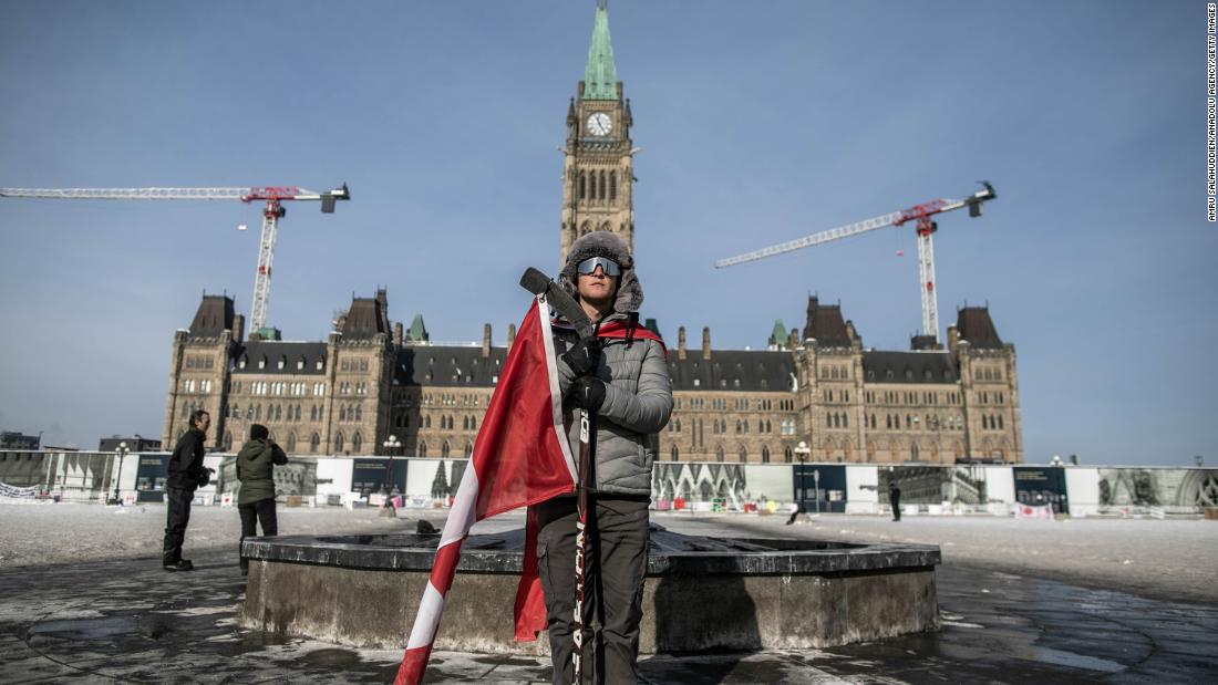 A protester stands with a Canadian flag in front of Parliament Hill in Ottawa.