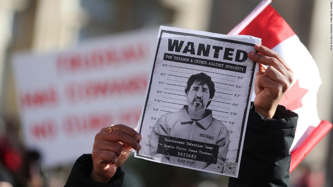 A protester holds up a wanted poster of Prime Minister Justin Trudeau as protesters gather around Queen&#39;s Park in Toronto on February 5.
