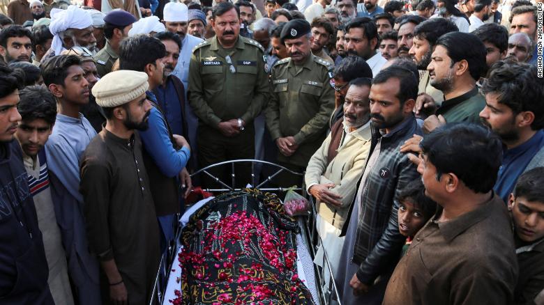 People stand beside the body of a man who, according to police, was lynched by a mob, in Tulamba Village, central Pakistan, on February 13, 2022. 
