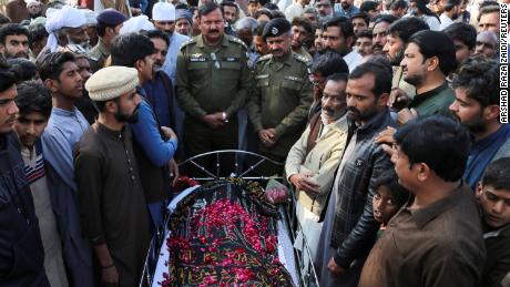 Des gens se tiennent à côté du corps d'un homme qui, selon la police, a été exécuté sommairement par une foule, dans le village de Tulamba, au centre du Pakistan, le 13 février 2022.