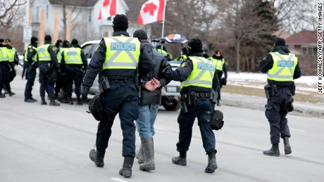 Police detain a protestor as they clear demonstrators against Covid-19 vaccine mandates who blocked the entrance to the Ambassador Bridge in Windsor, Ontario, Canada, on February 13, 2022.