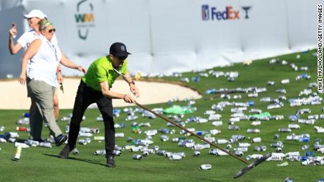 Groundskeepers pick up bottles thrown from the stands on the 16th hole after a hole-in-one by Sam Ryder.