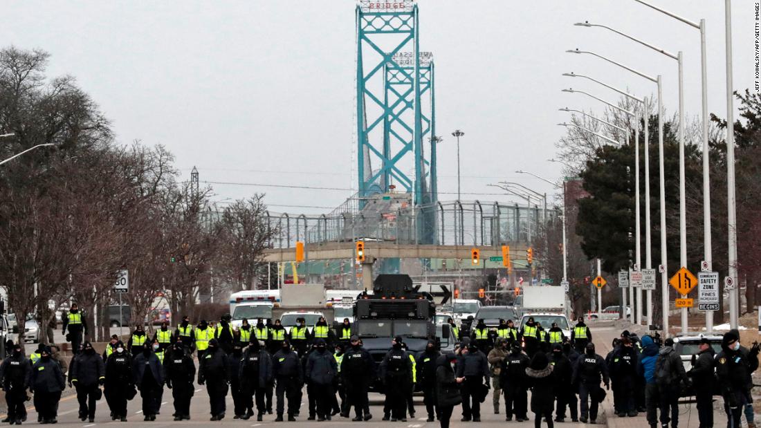 Police gather to clear protesters who blocked the entrance to the Ambassador Bridge in Windsor, Ontario, on Sunday, February 13. The Ambassador Bridge, North America&#39;s busiest land border crossing, reopened Sunday.