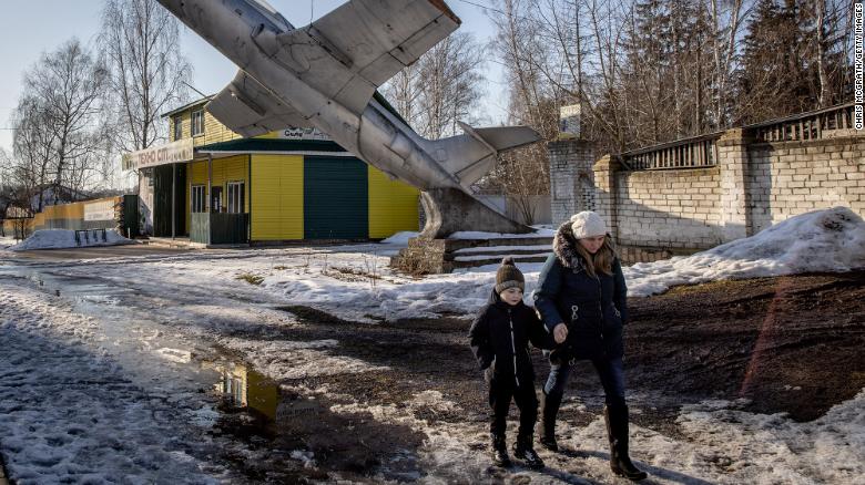 A woman and child walk underneath a military monument in Senkivka, Ukraine, on Monday, February 14. It's on the outskirts of the Three Sisters border crossing between Ukraine, Russia and Belarus.