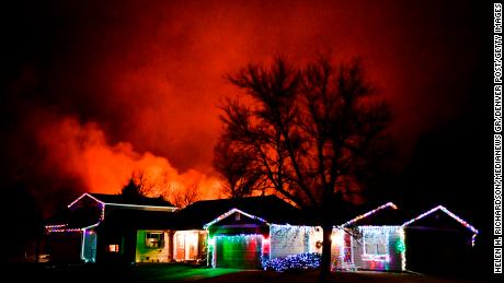 Christmas lights adorn a home as fires rage in the background as the Marshall Fire did not subside overnight.