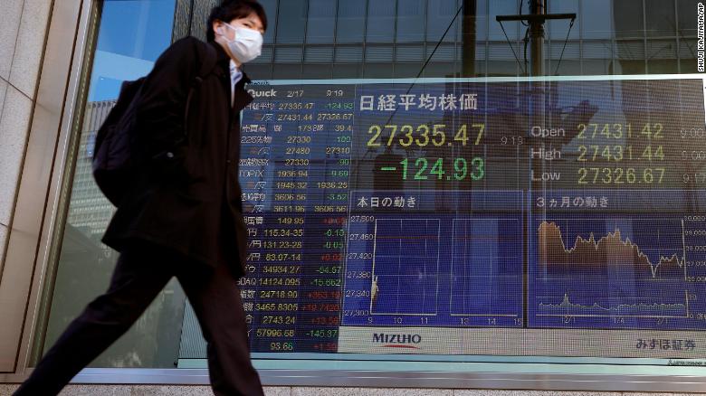 Un peatón pasa frente a un monitor que muestra el índice Nikkei 225 de Japón, en una firma de valores en Tokio, el jueves 17 de febrero de 2022.