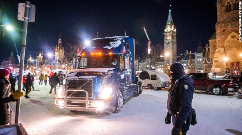 Ein Polizist beobachtet, wie ein Lastwagen am Freitag, den 18. Februar, den Parliament Hill in Ottawa verlässt.